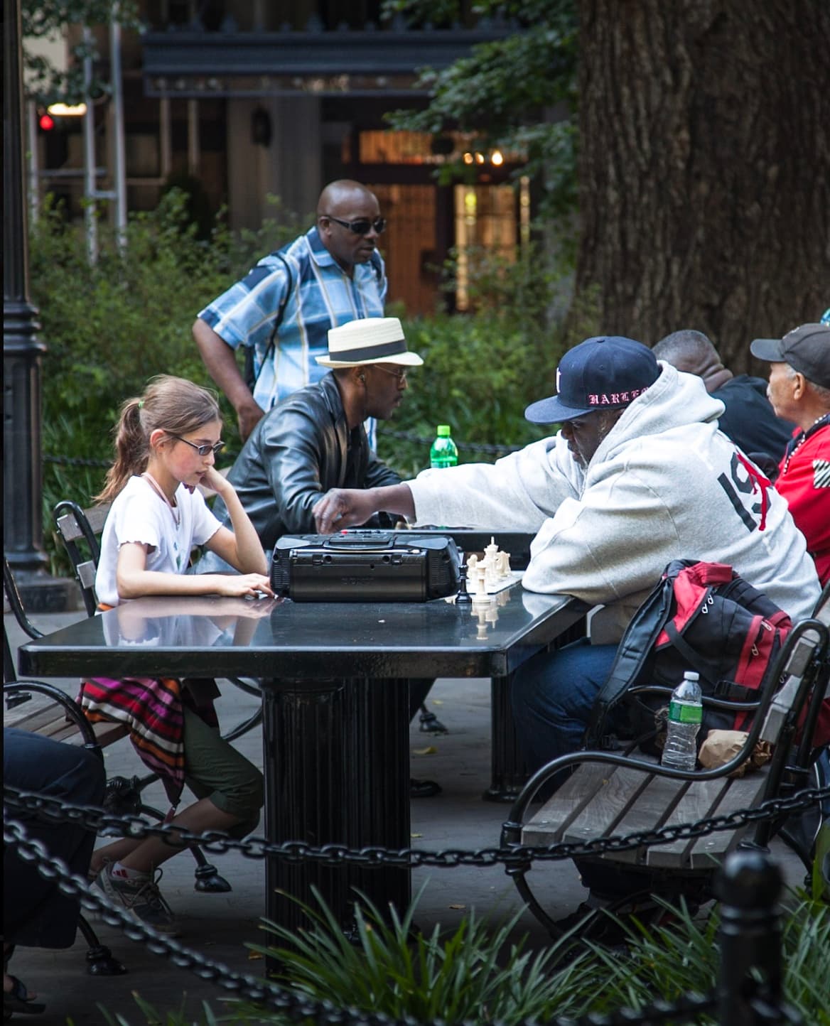 A young girl playing chess with a man at a public table in New York