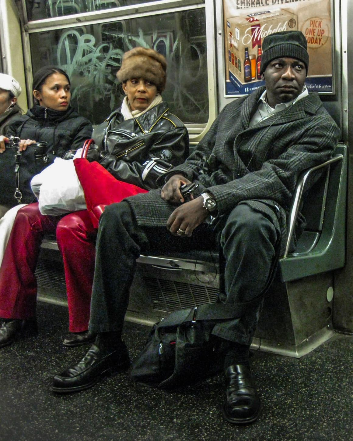 Three riders seated together on a New York subway car